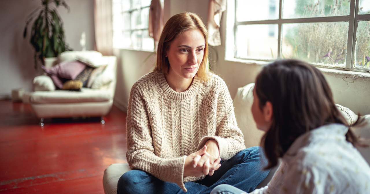 A mother and her daughter sit on the sofa and chat. 