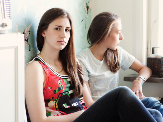 Two frustrated teens sitting on a bed