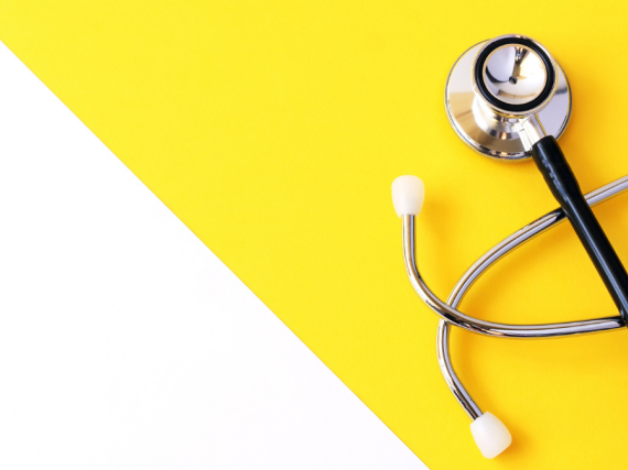 A stethoscope sits on a yellow and white background. 
