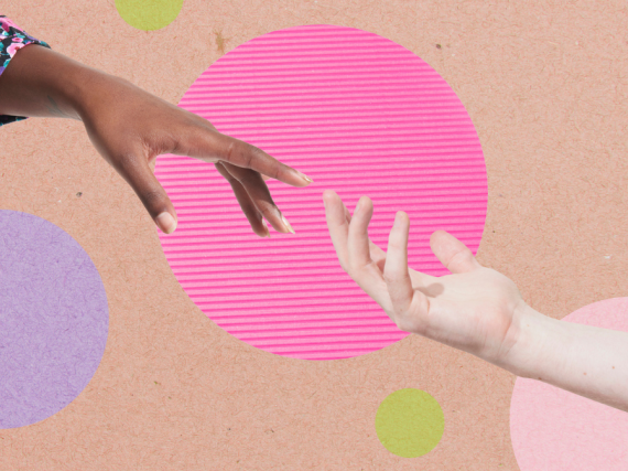 Two hands reach out to another another in front of a polka dotted background. 