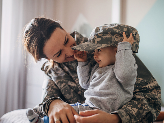 A female Marine smiles and laughs with her young son. 
