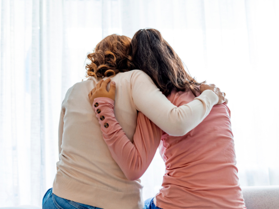 A photo of the backs of a mom and daughter hugging. 