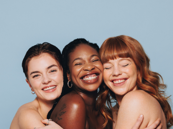 Three woman smile for the camera while hugging each other.