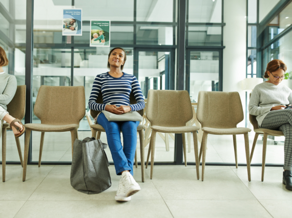 Three students sit in a waiting room at their college campus' health center. 