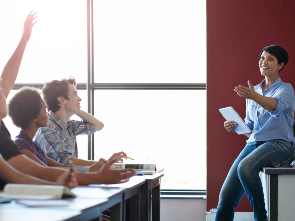 A classroom of students engaging with a smiling teacher